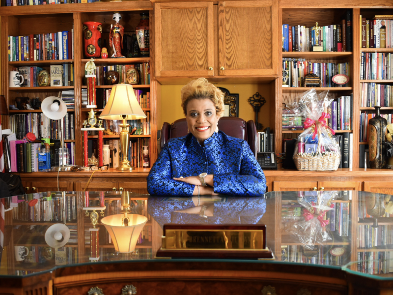 Rev. Dr. Brennetta Williams at desk in front of bookshelves