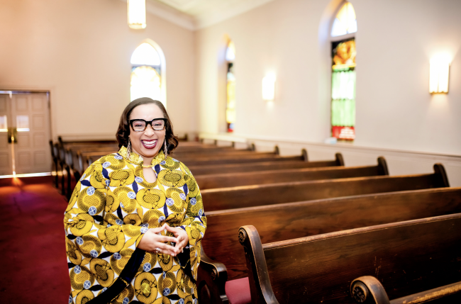 Pastor Littycia Clay-Crawley standing in the church pews