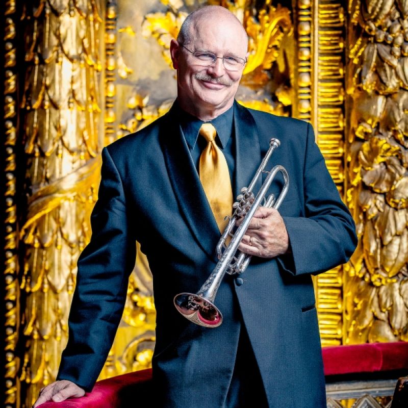 headshot of man in glasses holding trumpet