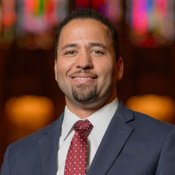 Luke Powery headshot in Duke Chapel; he is wearing a suit and red tie