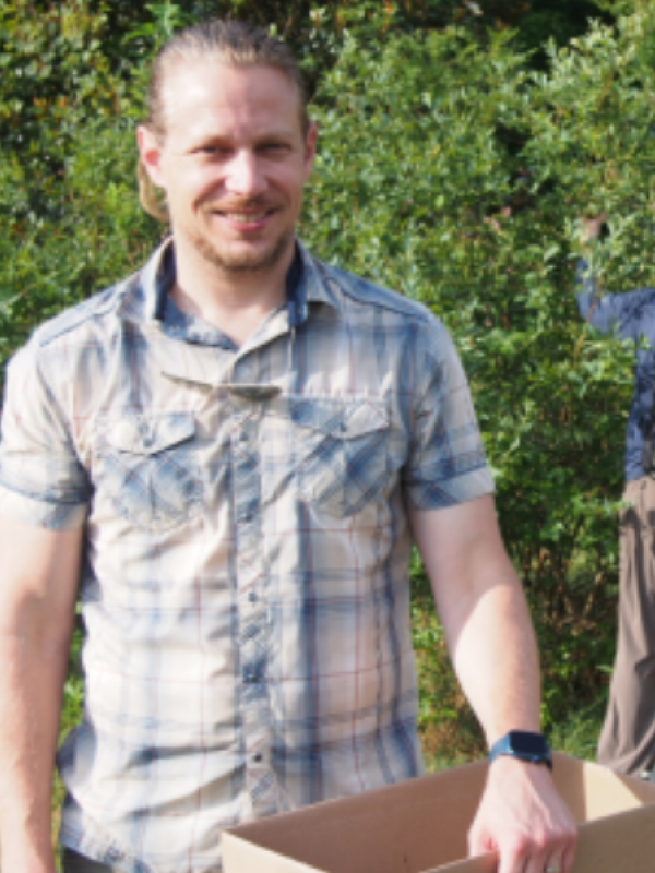 Andrew Lauber headshot in plaid shirt holding a box of blueberries