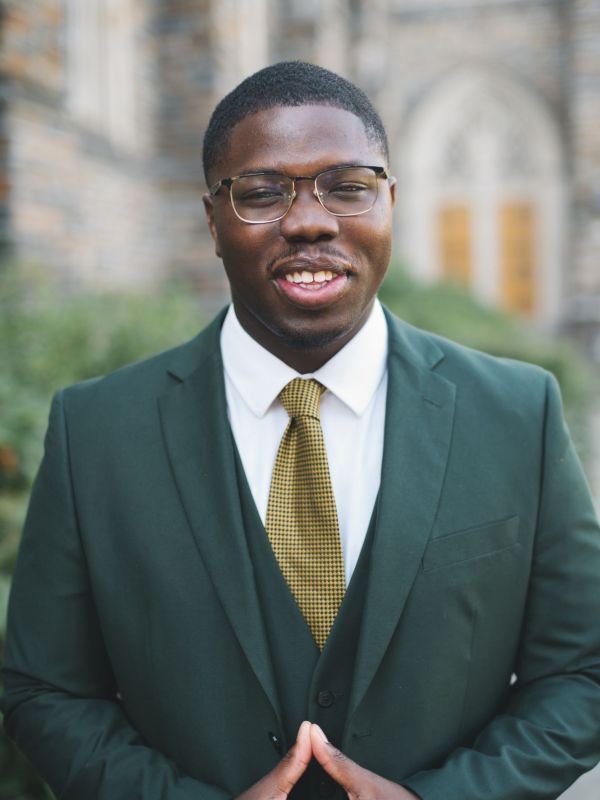 Justice Hill headshot in green suit and yellow tie