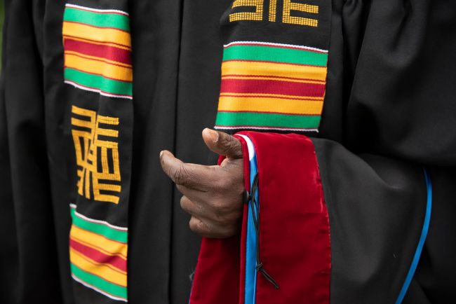 A Black student wears OBCS robes in traditional colors