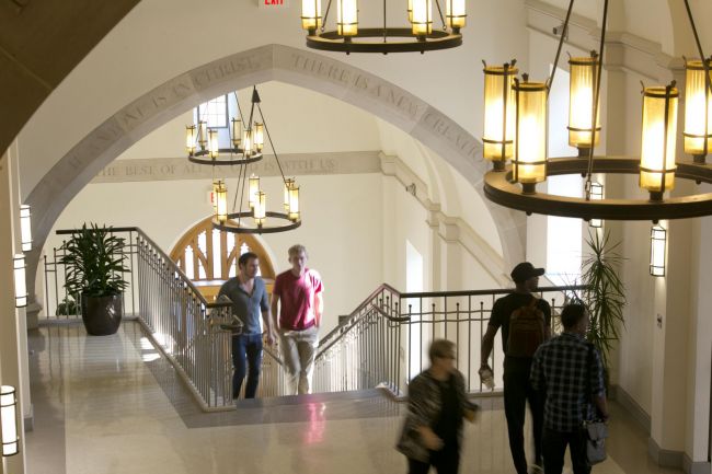 Students walk down the westbrook staircase with carved stone arches