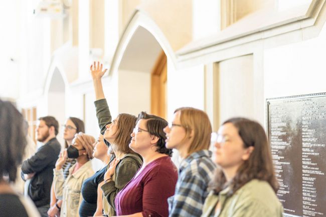 Students attend worship service in Goodson Chapel and one raises a hand up