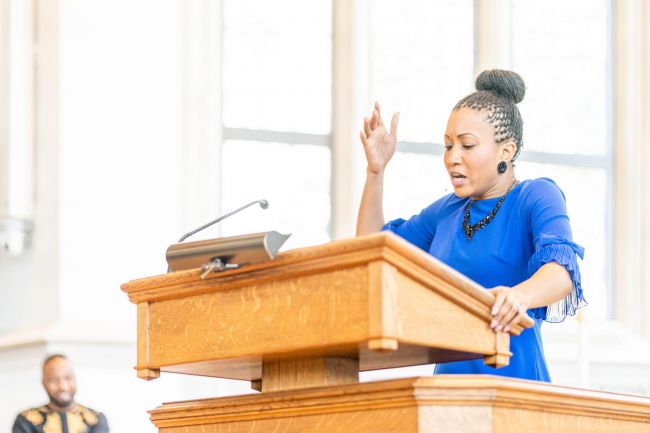 Elizabeth Styron Howze, M.Div. '17 wears a blue dress and preaches in Goodson Chapel