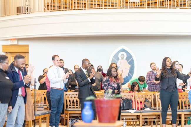 Students worship in Goodson chapel, standing and clapping