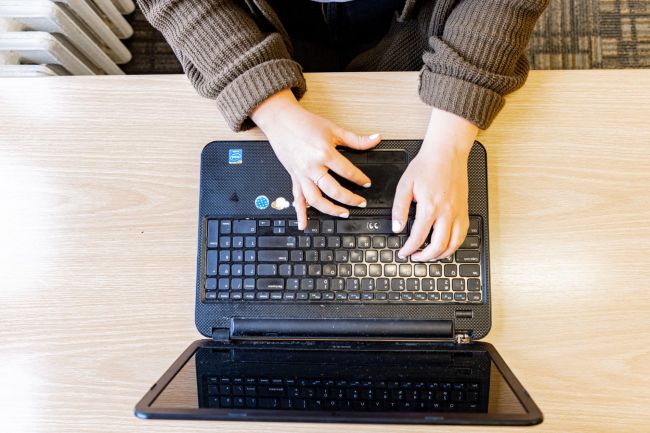 Hands type on a laptop, seen from overhead
