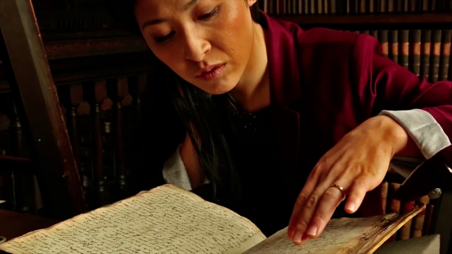 Polly Ha poring over an ancient book in a library