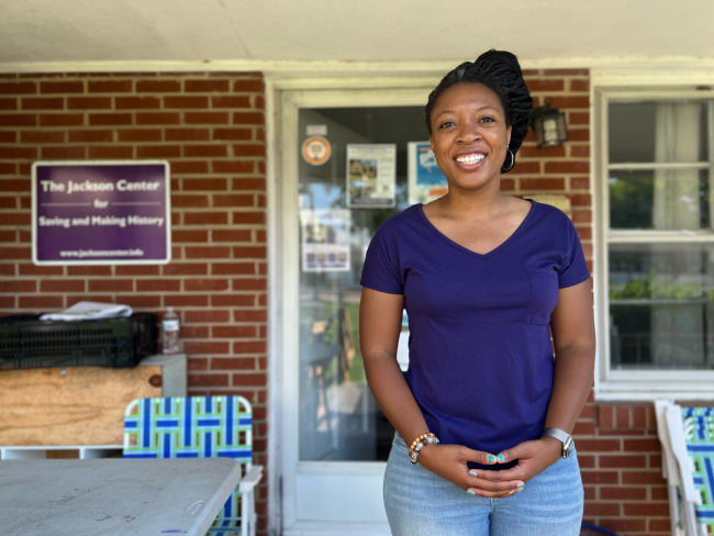 Jilian Palmer wears a purple shirt and jeans and stands in front of the Jackson Center in Chapel Hill.