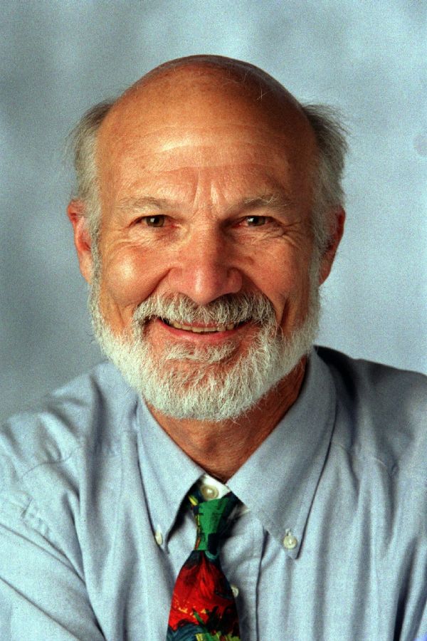 Stanley Hauerwas headshot in blue shirt and red and green tie