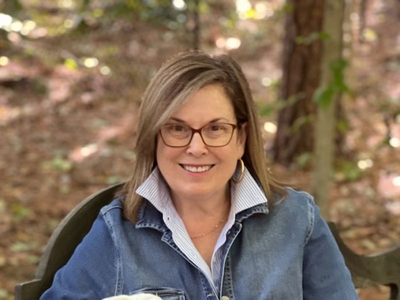 Robin Liles smiles in glasses and a collared blue shirt and jacket.
