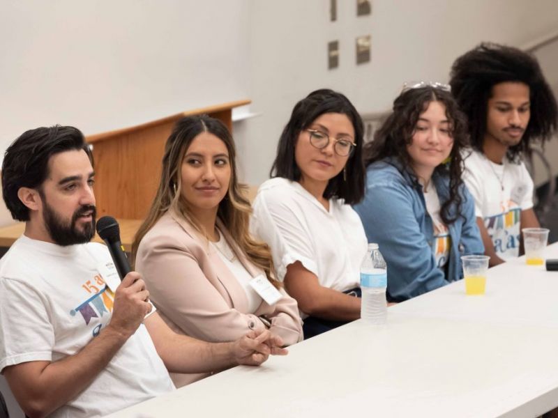 Students speaking at Hispanic House panel; student on the far left talks into the mic with four students sitting to his right