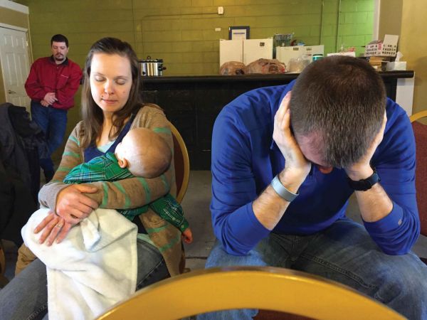 Brenna and Caleb Bennett, with one of their foster children, pray during a service at Christ-Reconciled.