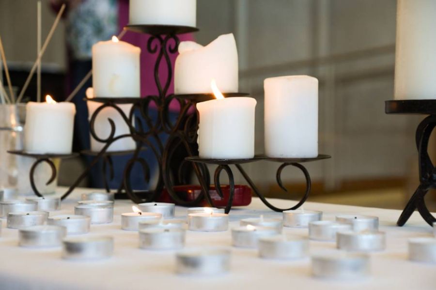 White pillar candles on a table surrounded by tealight candles.