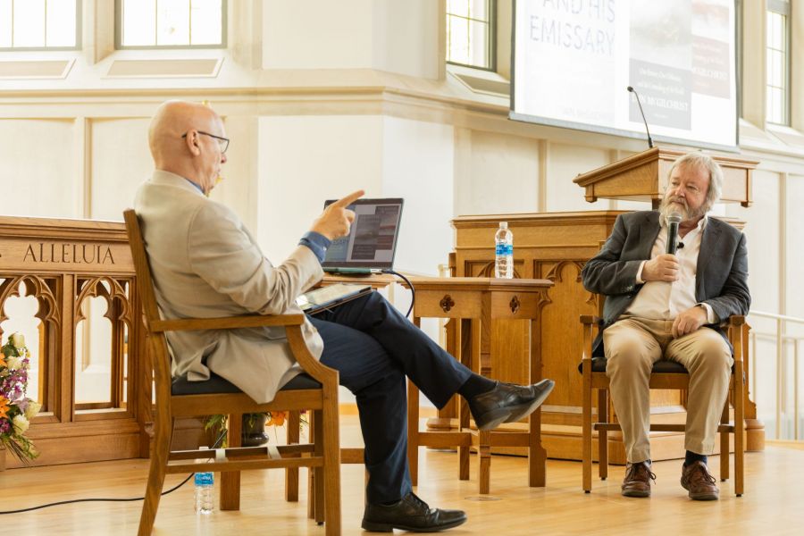 Men on stage discussing a book
