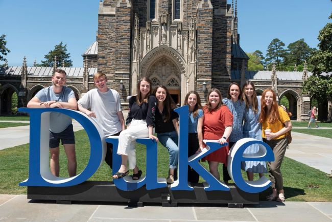 2024 graduating students pose outside of Duke Chapel with the "Duke" sign