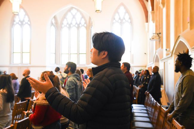 Student in worship with hands raised in Goodson Chapel