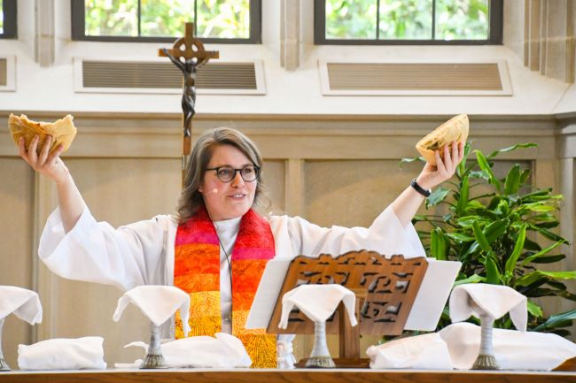 The Rev. Sarah Belles holds up the bread as she presides over Communion in Goodson Chapel