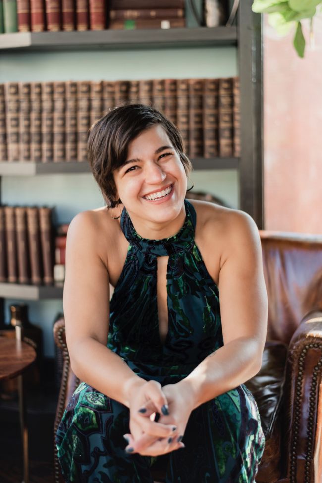 Anna Gazmarian sits in a chair looking at the camera, smiling