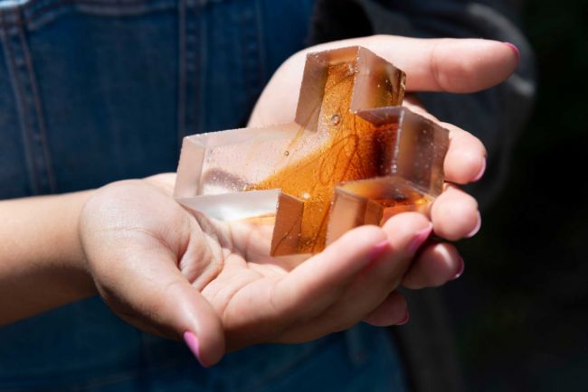 Hands holding a clear and orange glass cross