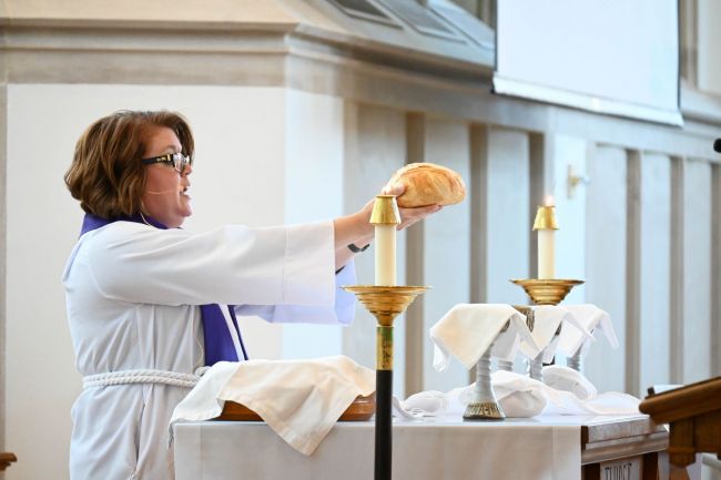 Meghan Benson holds up loaf of bread for communion during the Women's Center 50th Anniversary