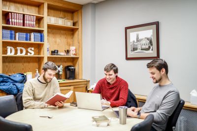 Three male students are studying together inside the Baptist House of Studies room at Duke Divinity