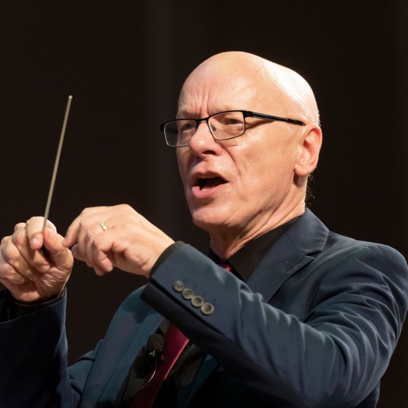 close up of man in glasses with conducting baton