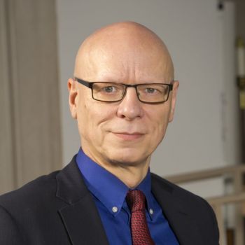 Jeremy Begbie wearing a dark suit, blue shirt, and wine colored tie in Goodson Chapel