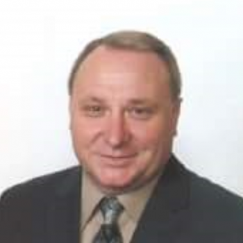 Dale Switzer wearing a tan shirt and tie with a dark blazer