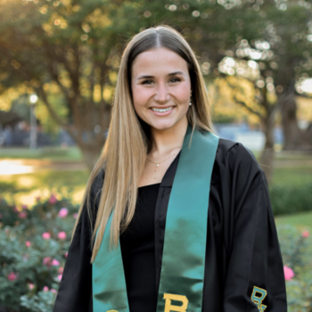 Emma Lindahl smiling wearing a black graduate gown and green Baylor University sash
