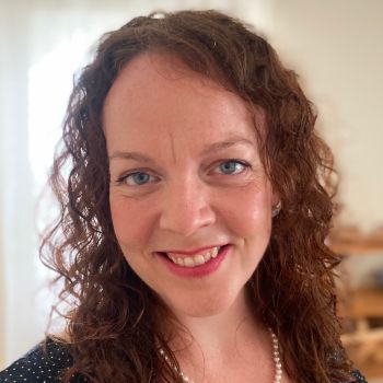 Heather Plonk smiling wearing a navy shirt and white pearl necklace