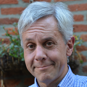 Jeff Baker smiling in a blue and white plaid shirt