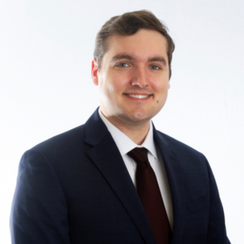 Joshua Duensing wearing a navy blazer and burgundy tie