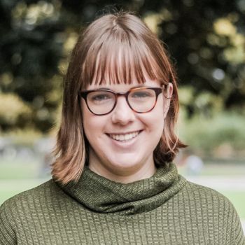 Julia Powers wears an army green turtleneck sweater and glasses