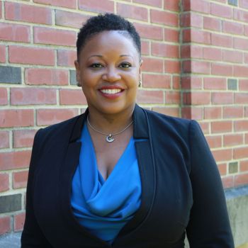 Keisha Bentley-Edwards smiling wearing a royal blue shirt and black blazer