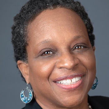 Lisa Robinson smiling wearing a black top and white pearl necklace