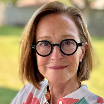 Melissa Grimes wearing a colorful blouse and black rimmed glasses