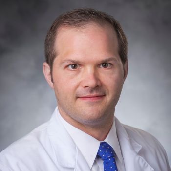 Thomas Longo wearing a blue tie and white medical coat