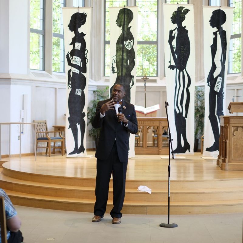 man speaking in front o flarge artworks