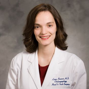 Liana Puscas wearing a red sweater under a white medical coat