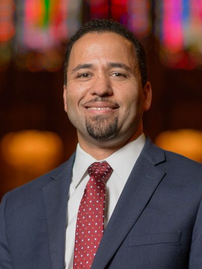 Luke Powery headshot in Duke Chapel; he is wearing a suit and red tie