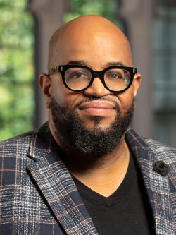 Eric Lewis Williams, director of the Office of Black Church Studies and assistant professor of theology and Black Church studies, in black shirt and black rimmed glasses